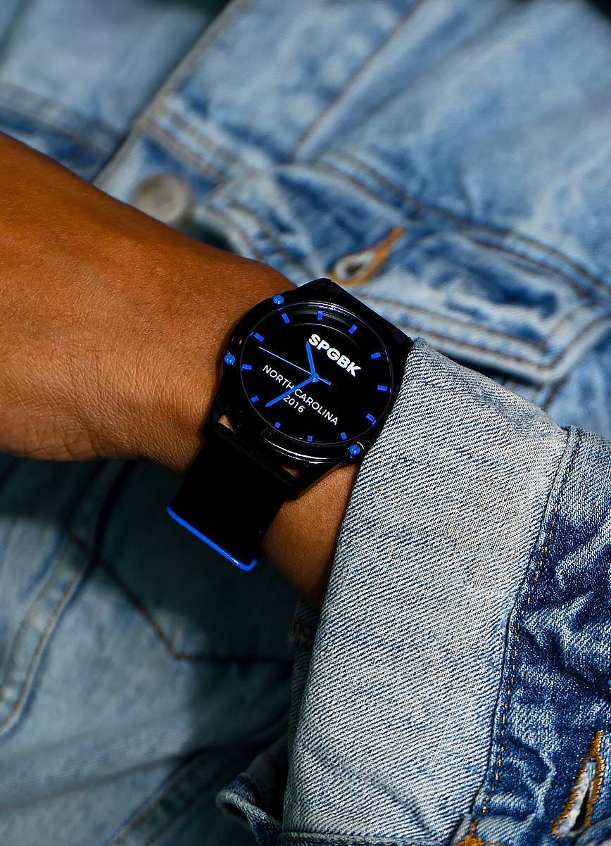 Person wearing a black smartwatch with blue accents on a denim background