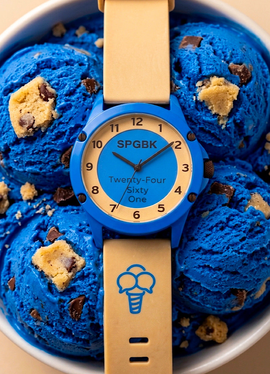 Blue watch with beige strap on a bowl of blue ice cream with cookie dough pieces